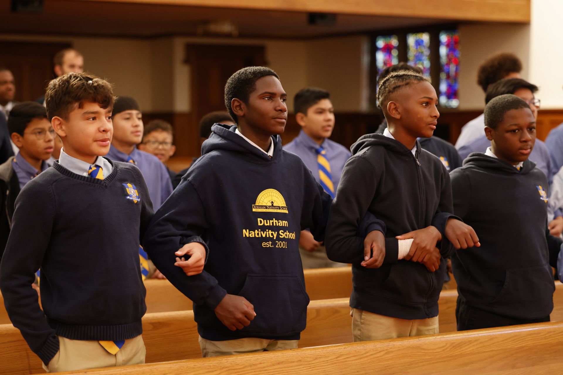 students linking arms in church pew